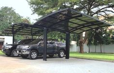 two trucks are parked under a metal carport