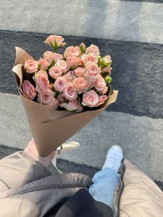 someone holding a bouquet of pink roses on their hand while walking down the stairs outside