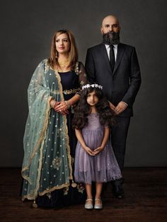 a man and two women standing next to each other in front of a dark background