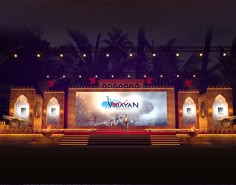 an outdoor stage set up for a concert with lights on and people standing in front