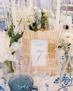 the table is set with blue and white floral centerpieces, wicker basket for seating