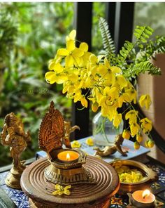 yellow flowers and candles are on a table