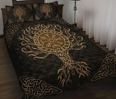 a bed covered in a black and gold comforter with an intricate design on it