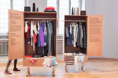 a person walking past two open closets with clothes hanging on the racks and an ottoman