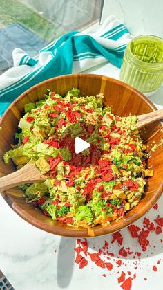 a wooden bowl filled with lettuce and tomato salad on top of a table