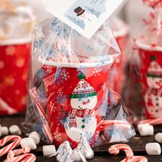 a cup filled with candy canes sitting on top of a table next to other cups