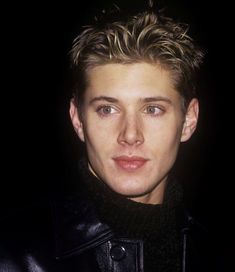 a close up of a person wearing a leather jacket and looking at the camera with a serious look on his face