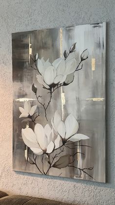 a painting hanging on the wall with white flowers