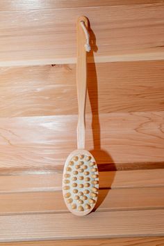 a wooden brush with white dots on it hanging from a wood wall next to a string