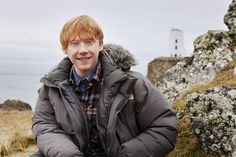 a young man standing in front of some rocks