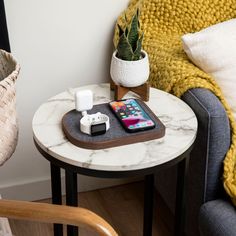 a table with a cell phone on it next to a chair and potted plant