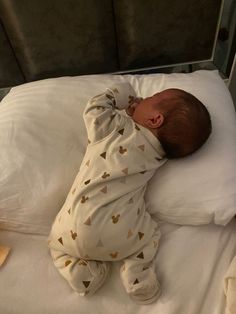 a baby sleeping on top of a white bed