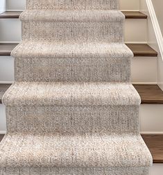 a carpeted staircase with white handrails and beige carpet on the bottom step