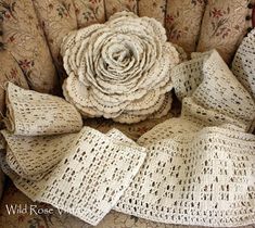 a white rose sitting on top of a chair next to some laces and fabric