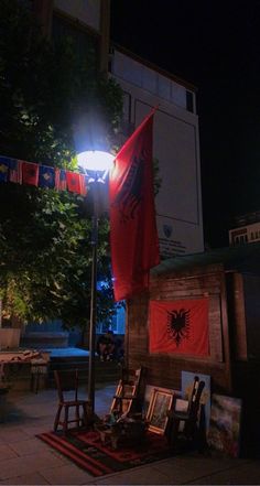 a red flag and some pictures are on the ground in front of a building at night