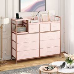 a living room with a pink dresser and pictures on the wall, coffee table and rug