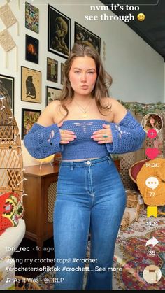 a woman is standing in front of a wall with pictures on it and holding her hands to her chest