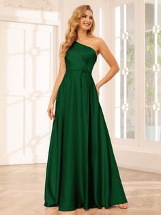 a woman in a long green dress posing for the camera with her hands on her hips