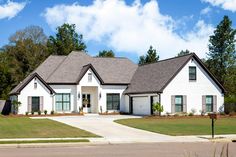 a large white house with lots of windows and grass in front of the door is surrounded by trees