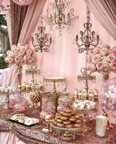 a table topped with lots of desserts and candies next to a chandelier