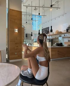 a woman sitting on top of a chair in a room next to a white table