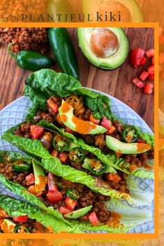 lettuce wraps filled with meat and vegetables on top of a wooden table next to an avocado