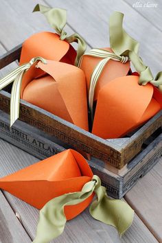 two orange paper hearts in a wooden box with ribbon on the top and green bows tied around them