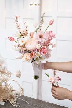 a bouquet of flowers is being held by someone's hand on top of a table