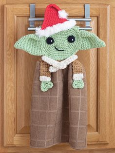 a crocheted star wars yoda hanging from a hook on a wooden door