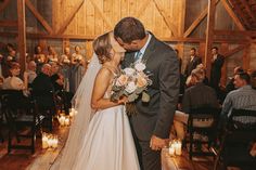 a bride and groom kissing in front of an audience at a wedding ceremony with candles on the floor