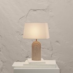 a table lamp sitting on top of a white box next to a light fixture with a beige shade