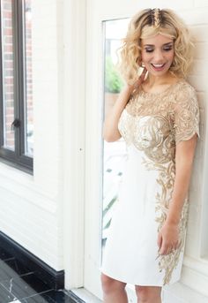 a woman in a short white dress leaning against a wall