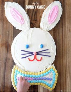 a bunny cake with white frosting and colorful candies on it, ready to be eaten