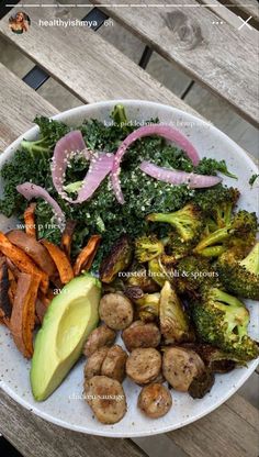 a white plate topped with broccoli, carrots and other foods on top of a wooden table