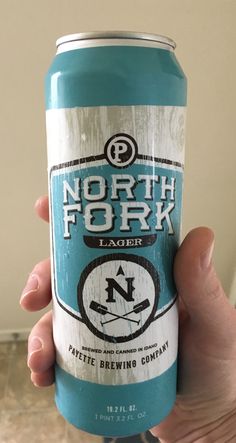 a person holding up a can of north fork lager