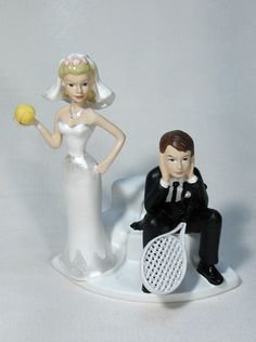 a wedding cake topper with a bride and groom holding tennis racquets