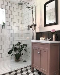 a bathroom with black and white tile flooring and a pink cabinet in the corner