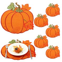 an orange place mat with pumpkins and leaves on it next to a white plate