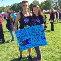 two people standing in the grass holding a sign