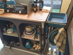 a kitchen area with dishes, cups and utensils on the counter next to an rv door