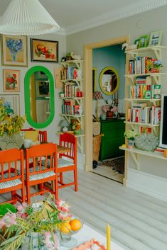 a living room filled with furniture and bookshelves next to a doorway that leads into a dining room