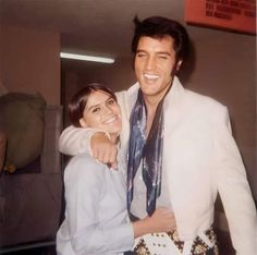 a man and woman standing next to each other in front of a mirror smiling at the camera