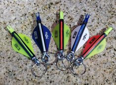 four different colored paddles with metal handles on a granite countertop next to pens and scissors