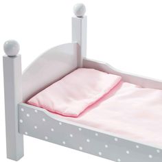 a white bed with pink sheets and polka dots on the headboard is shown in this image