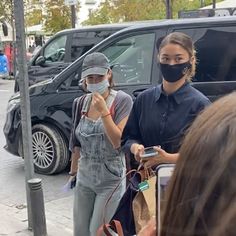 two women wearing face masks while walking down the street