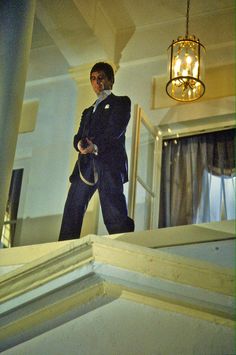 a man in a suit and tie standing on the edge of a window sill