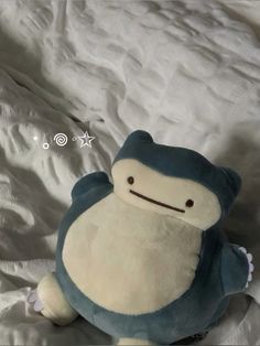 a blue and white stuffed animal sitting on top of a bed