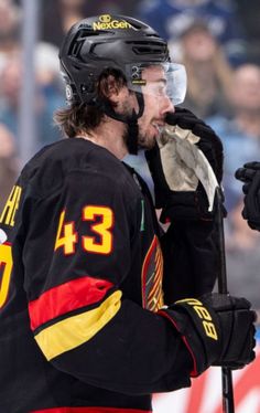 the hockey player is holding his helmet and looking at something in front of him as he stands on the ice