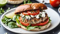 a chicken burger with tomatoes, lettuce and feta cheese on a plate