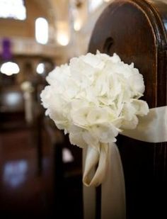 a bouquet of white flowers sitting on the back of a church pew